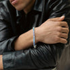 Person wearing a blue iced bracelet and a black jacket