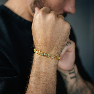 Close-up of a person's wrist wearing a gold bracelet with a blurred background