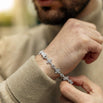 Person wearing a delicate iced silver bracelet with a blurred background