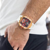 The Intrepid Sport - Ice White men's luxury watch featuring a bold rose gold-tone case, black and red dial with chronograph subdials, and a white strap, worn on wrist.