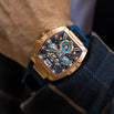 The Intrepid Sport - Rose Gold men's luxury watch with a bold rose gold case, blue dial featuring 24-hour, day, and date subdials, and a blue strap, worn on wrist.