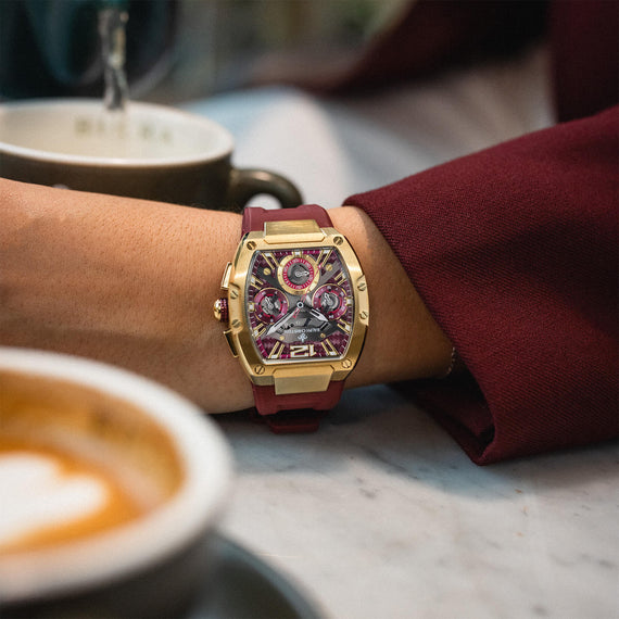 The Intrepid Sport Ladies - Scarlet Gold by Ralph Christian on wrist with a gold case red strap and detailed chronograph dial in a cafe setting