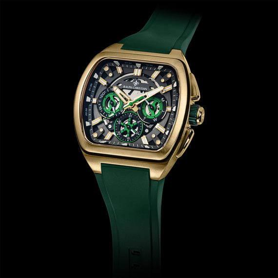 A luxury watch with a gold-tone rectangular case, a dark dial featuring green subdials and luminous markers, and a dark green silicone strap, shown against a solid black background.