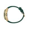 A close-up rear view of a watch with a dark green silicone strap and a gold-tone case, featuring a crown guard and a circular logo medallion on the side.