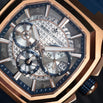 Luxury watch with rose gold case and blue accents on a dark background