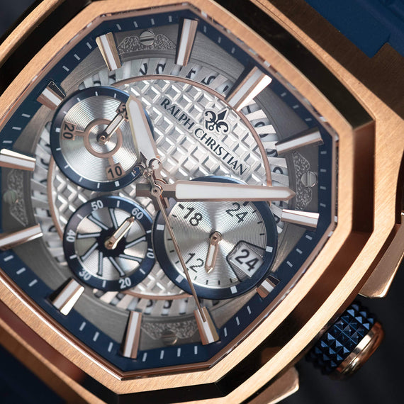 Luxury watch with rose gold case and blue accents on a dark background