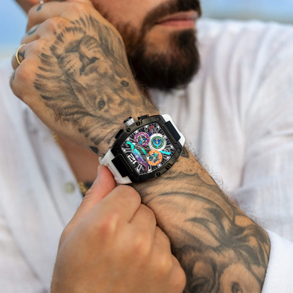 The Intrepid Sport - Aurora Burst men's luxury watch featuring a bold black case, multicolored dial with day and date functions, and a contrasting white strap, worn on a tattooed wrist.