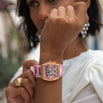 The Intrepid Sport Ladies - Rose Petal features a bold rose gold case with a pink dial, day and date functions, and a soft pink strap, worn on wrist with stylish gold ring and white blouse, embodying a statement women's luxury watch by Ralph Christian. Bold by Design.