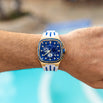 The Legacy Chrono Ice - Sapphire Royale men's luxury watch featuring a bold blue dial with chronograph subdials, gold-tone case, sapphire-coated crystal, and white strap with blue accents.