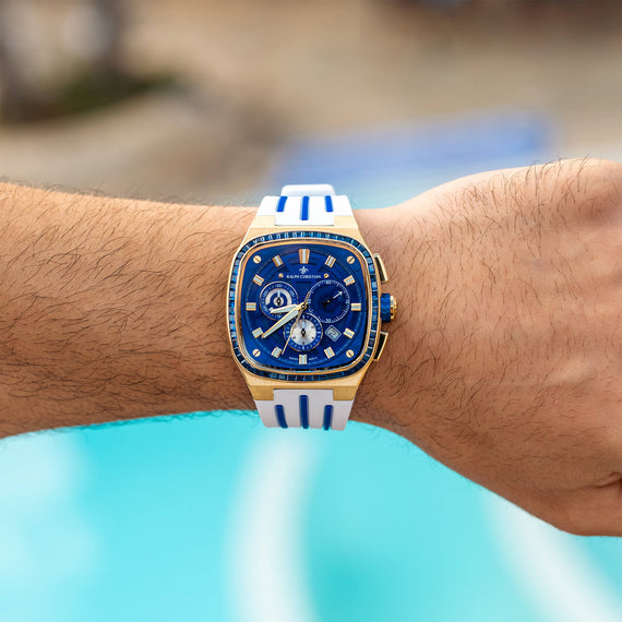 The Legacy Chrono Ice - Sapphire Royale men's luxury watch featuring a bold blue dial with chronograph subdials, gold-tone case, sapphire-coated crystal, and white strap with blue accents.