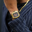 The Polaris Chrono - Obsidian Black men's luxury watch features a bold gold case, black dial with chronograph subdials, and a black strap, styled with a pinstripe blazer.