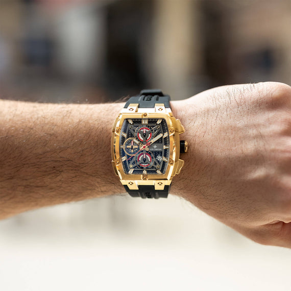 The Polaris Chrono - Obsidian Black men's luxury watch with a bold gold-tone case, black dial featuring chronograph subdials, and a black rubber strap, worn on wrist.
