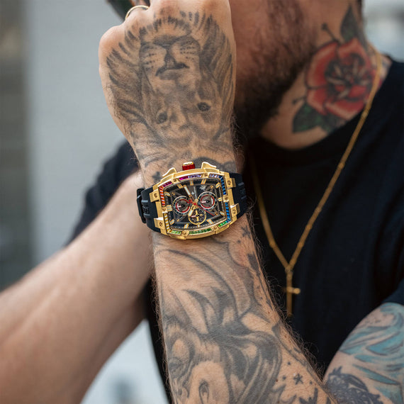 Person wearing a gold and black watch with tattoos on their arm.