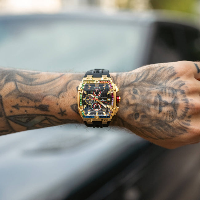 Gold and black wristwatch on a tattooed arm with a blurred background