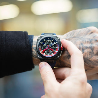 Person wearing a black and red watch with a blurred background