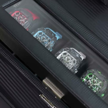 Set of four bold statement watches with square cases and visible chronograph subdials in red, blue, silver, and green, displayed in a luxurious black presentation box.