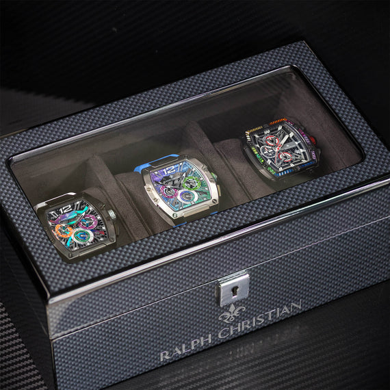 Luxury Collectors Watch Case with carbon fiber textured exterior and clear display lid, showcasing three automatic chronograph watches with colorful dials inside.